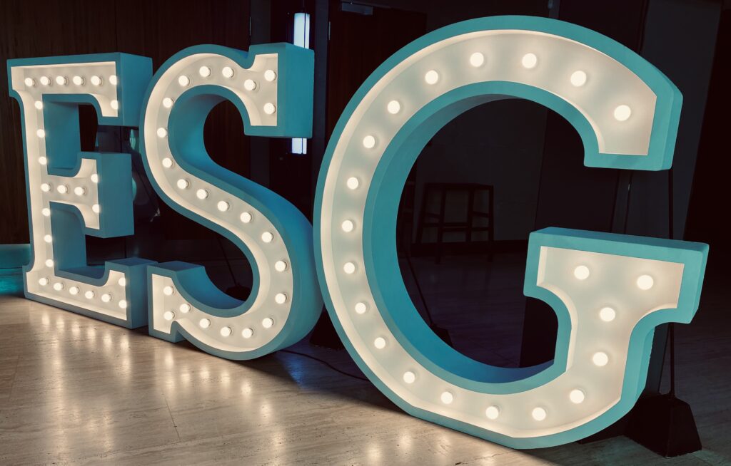 Illuminated letters spelling 'ESG' at a conference event, showcasing a focus on Environmental, Social, and Governance topics.